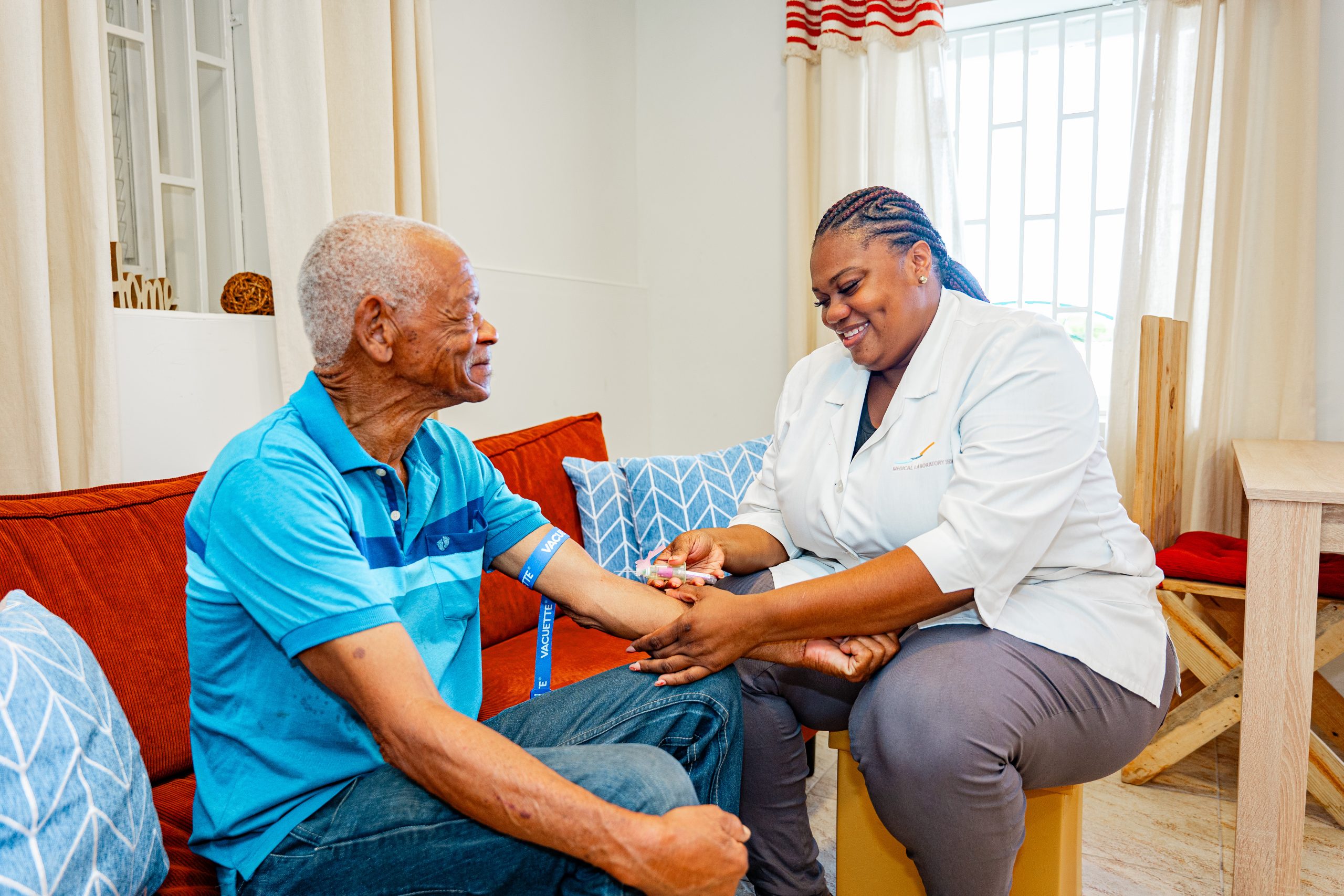 Employee of Medical Laboratory Services Curaçao taking a blood sample of a patient in the comfort of their own house.